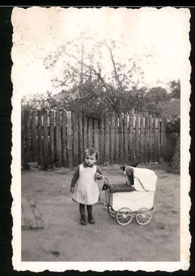 Photography: Girl playing with a doll’s pram in the garden