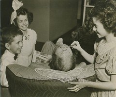 Children drawing face on bald head antique photo